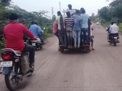 Dangerous journey of laborers hanging from vehicle on Surat-Nagpur highway | सुरत-नागपूर महामार्गावर मजुरांचा वाहनाला लटकून धोकेदायक प्रवास