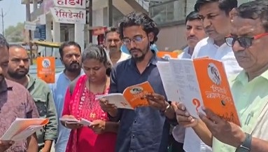 चिखली शहरातील चौफुलीवर पुस्तकाचे वाचण करतांना प्रशांत अंबी व सहकारी.