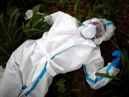 Viral photo of health worker who rests prior to the burial of women body who died due to corona | Coronavirus: कोरोनाग्रस्त महिलेचा मृतदेह दफन करण्यापूर्वी थकलेला कोविड योद्धा जमिनीवर पडला, अन्...