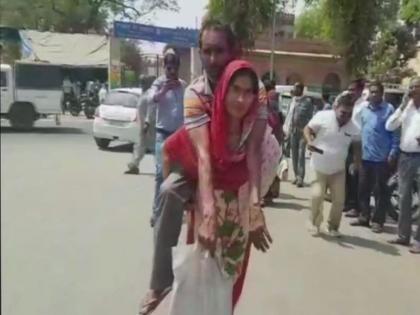 woman carrying her differently abled husband on her back to office of chief medical officer to obtain a disability certificate | व्हीलचेअर नसल्यामुळे महिलेला करावे लागले 'दिव्य'; नवऱ्याला पाठीवरून आणले सरकारी कार्यालयात