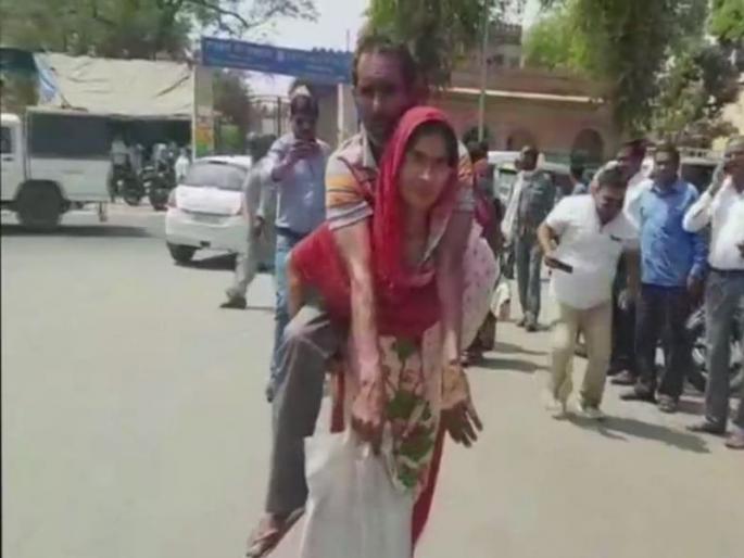 woman carrying her differently abled husband on her back to office of chief medical officer to obtain a disability certificate | व्हीलचेअर नसल्यामुळे महिलेला करावे लागले 'दिव्य'; नवऱ्याला पाठीवरून आणले सरकारी कार्यालयात