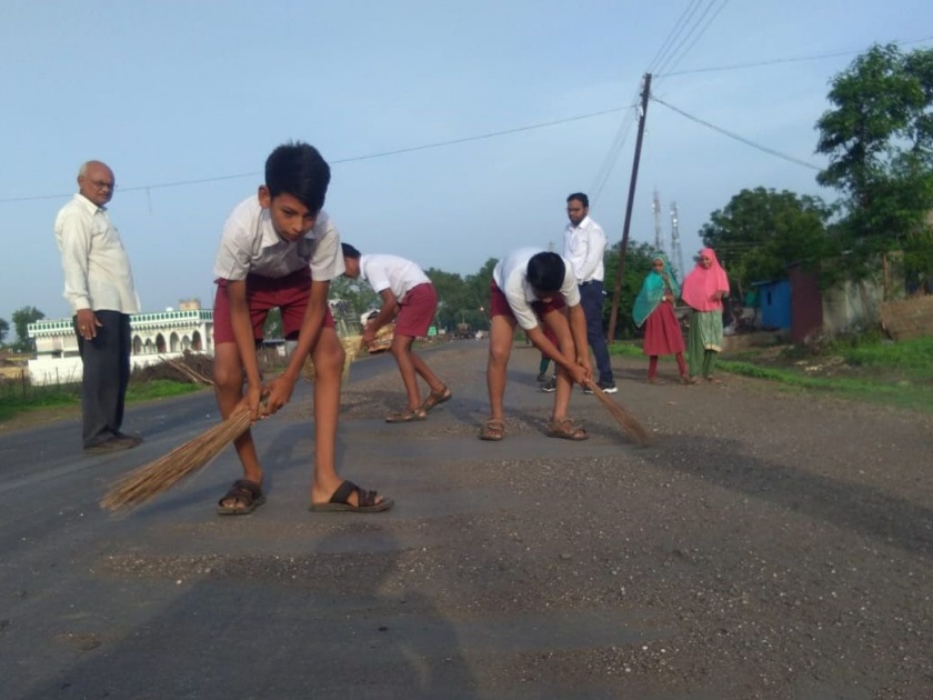 The social commitment of the students is filled with scattered sand on the state road | राज्य मार्गावर विखुरलेली वाळू झाडून विद्यार्थ्यांनी जपली सामाजिक बांधिलकी