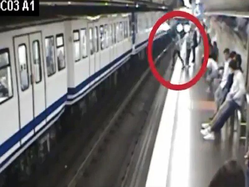 spain madrid woman busy on phone falling in front of train viral video | मोबाईलमध्ये बघत चालताना ट्रॅकवर पडली, समोरून ट्रेन आली, अन्...