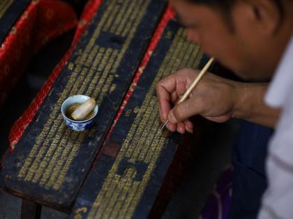 Artists in Nepal repaint Buddhist manuscript with gold as religious rituals halted for month | Artists in Nepal repaint Buddhist manuscript with gold as religious rituals halted for month