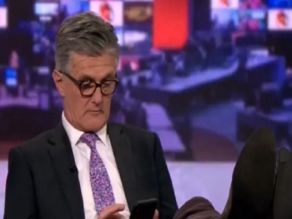 BBC presenter caught on camera scrolling phone with feet up on desk | लाइव प्रसारण के बीच मेज पर पैर रखकर मोबाइल में बिजी दिखा एंकर, सोशल मीडिया पर मजेदार वीडियो वायरल