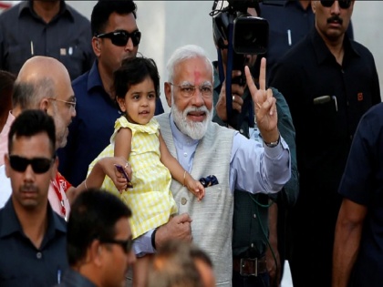 PM Modi plays with Amit Shah's granddaughter votes in Gujarat ls polls 2019 | अमित शाह की पोती को यूं गोद में खिलाते दिखे पीएम मोदी, तस्वीरें हुई वायरल 