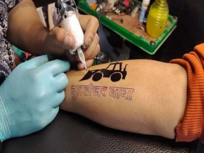 Tattoo of Bulldozer Baba spread in Varanasi demand suddenly increased after BJP up victory People are seen walking on the Assi Ghat sp akhilesh yadav | Bulldozer Baba Tattoo: Varanasi में हर तरफ छाई 'बुलडोजर बाबा' के टैटू की धूम, BJP की जीत के बाद अचानक बढ़ गई मांग; हाथों में गुदवा कर अस्सी घाट पर घूमते दिख रहे हैं लोग